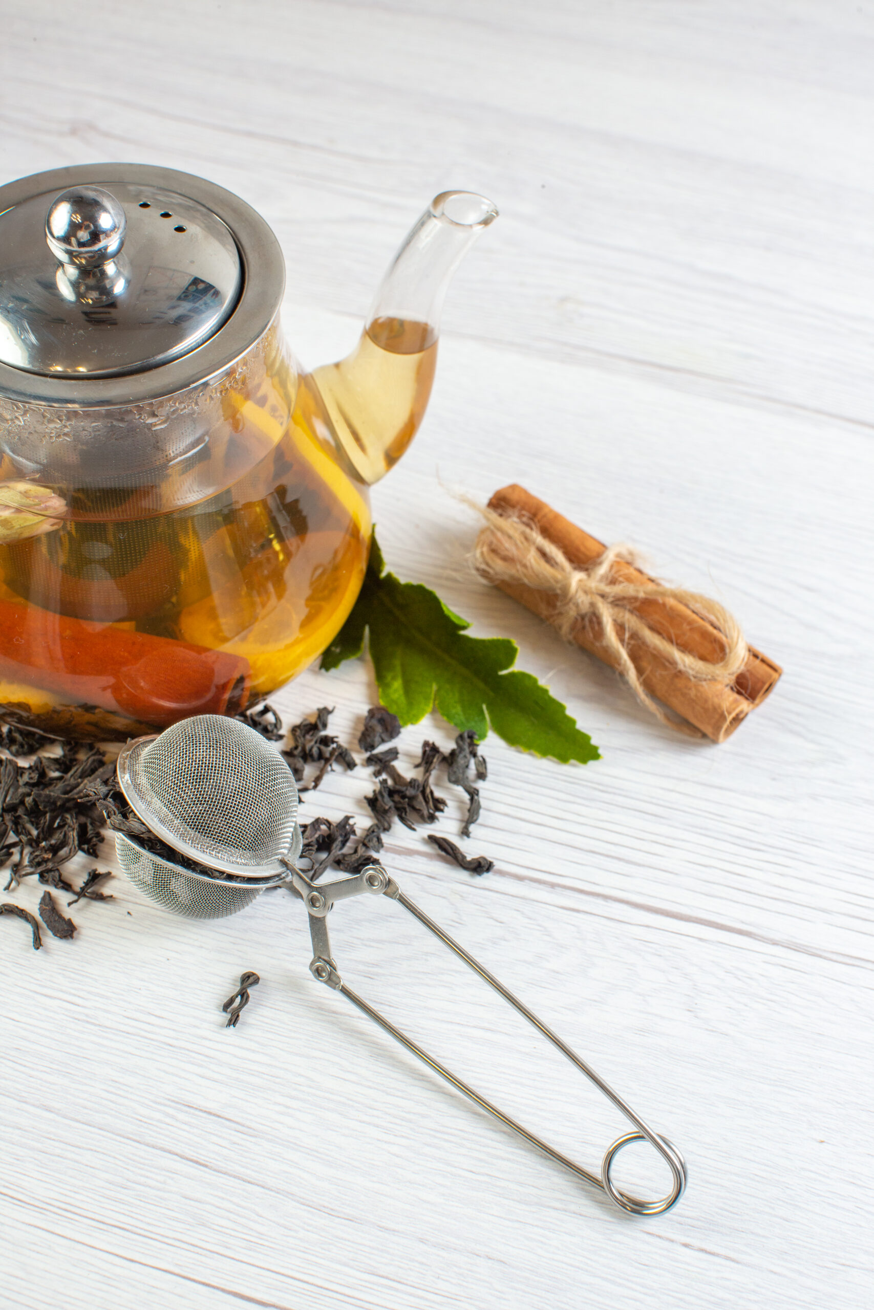 vertical view herbal tea glass pot cinnamon limes white background